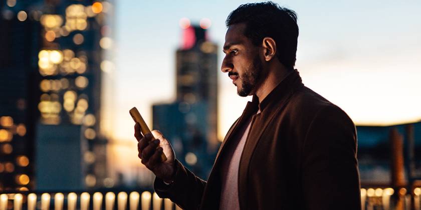 Cityscape at sunset with man looking at his mobile