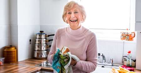 Smiling older woman drying dishes
