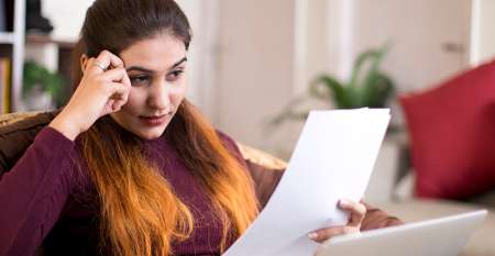 Woman with laptop reading a bill