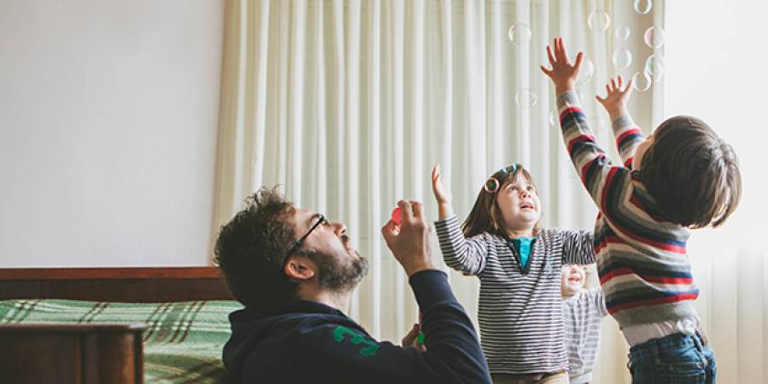 Man and 2 small children blowing bubbles