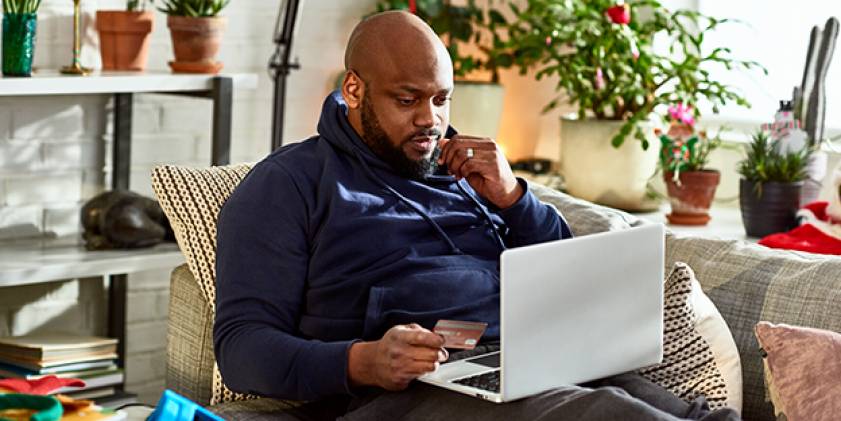 Man looking at laptop holding credit card