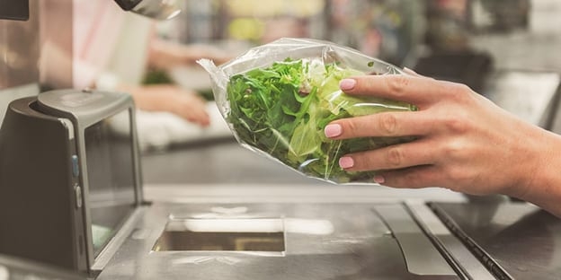 Woman's hand scanning pack of salad at self serve-checkout