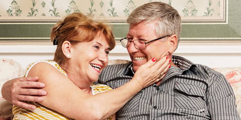 Older couple sitting on sofa laughing