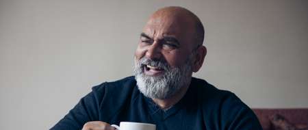 Grey bearded man holding mug